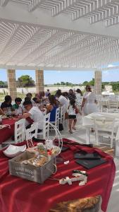 托雷圣乔万尼乌B&B Villa Serena Resort的一群坐在白色帐篷下桌子的人