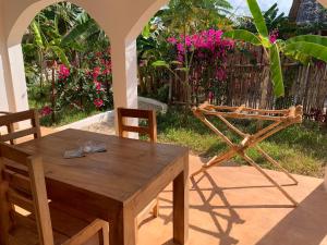 吉汶瓦Breeze Residence Apartments的院子里的一张木桌子和椅子,上面有粉红色的花朵