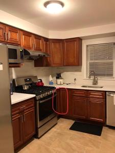 亨普斯特德纽约ZUHUA长岛(Hofstra University) （霍夫斯特拉大学）民宿！的厨房配有木制橱柜和带红色软管的炉灶。