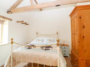 东迪勒姆The Stables的卧室配有白色的床和木制橱柜。