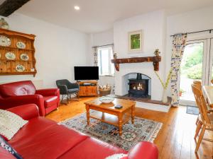 科尔雷恩Quiet Waters Cottage的客厅设有红色的沙发和壁炉
