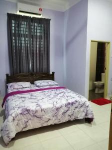 阿罗士打HOMESTAY DSUKA MENANTI的一间卧室配有一张带紫色和白色棉被的床