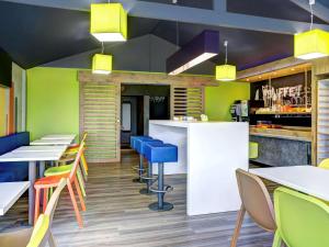 埃鲁维尔圣克莱宜必思卡昂爱荷维耶经济酒店的一间设有五颜六色桌椅的餐厅和一间酒吧