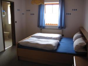 波滕施泰因Ferienwohnungen Haberberger的一间卧室配有一张带窗户和蓝色窗帘的床