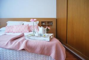 甘迪亚Encantadora Casa cerca del mar con piscina SOLO FAMILIAS的一间卧室配有一张带粉色床单的床和一个带鲜花的托盘