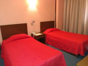 贾拉普哈拉帕维多丽亚酒店的红色床罩的酒店客房内的两张床