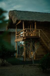 阿鲁甘湾Whisky Point Resort的茅草屋顶和甲板的小小屋