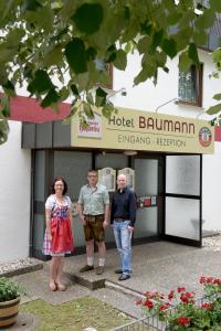 内卡河畔弗赖贝格Hotel - Restaurant Baumann的三个人站在酒店大楼前