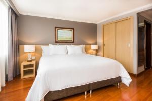 波哥大科斯莫斯100号酒店及会议中心的卧室配有一张白色大床和两盏灯。