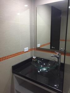 富萨加苏加Hotel Garden City Boutique的一间带玻璃水槽和镜子的浴室