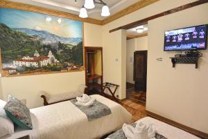 基多Hotel La Basílica Quito的客房设有两张床和一台墙上的电视。