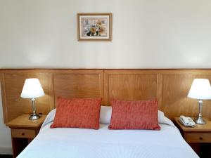 拉普拉塔贝内文托酒店的卧室配有带两盏灯的白色床
