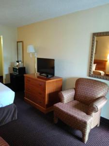 圣安东尼奥Knights Inn San Antonio near Frost Bank Center的酒店客房配有一张床、一把椅子和一台电视。