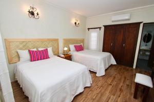 瓦哈卡市特雷沃尔酒店的一间卧室配有两张带白色床单和粉红色枕头的床。