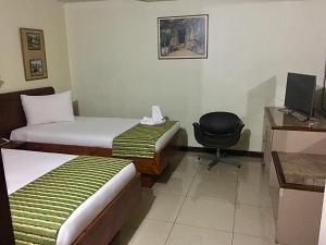 圣何塞Hotel Ambassador的酒店客房,配有两张床和椅子