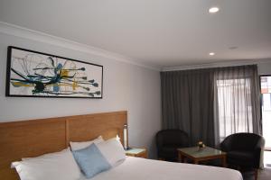 Quirindi奎林代RSL贝斯特韦斯特汽车旅馆的酒店客房设有一张床、两把椅子和一扇窗户。