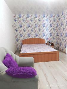 敖德萨Apartment - Generala Petrova Street的一间卧室配有一张床和一张带紫色枕头的沙发