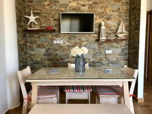 博罗尼亚Apartamento Triana II Bolonia, Tarifa的餐桌、椅子和石墙电视