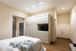 利沃诺Agave in Città的一间卧室配有一张床、一台电视和白色橱柜。