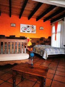 瓦斯卡坎波Namasté Cabañas, Huasca de Ocampo的橙色墙壁和桌子的客房内的两张床