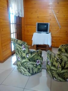 ItaaraPousada Taiani的客厅配有两把椅子和电视