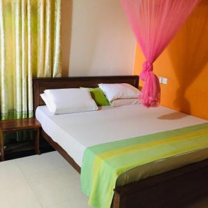 尼甘布蜜蜂巢住宿加早餐旅馆的一间卧室配有两张带粉红色窗帘的床