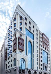 麦地那Tulip Inn Al Daar Rawafid的一座高大的白色建筑,设有玻璃窗