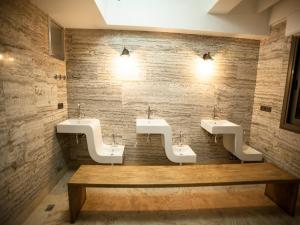 艾登Lion Park Suites & Residence Hotel的一间设有三个水槽和木板凳的公共浴室