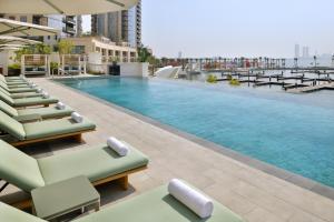 迪拜云溪港葳达酒店的一座带躺椅的建筑屋顶上的游泳池