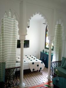 丹吉尔Dar Tinjâa的一间卧室配有一张白色柱子床和一张沙发。