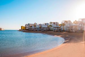 赫尔格达Sunrise Crystal Bay Resort -Grand Select的一片拥有部分房屋和水的海滩