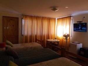 伊斯拉德迈波Alojamiento Valle Verde的一间卧室设有两张床,窗户配有电视。