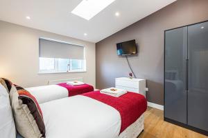 伦敦South Woodford 2 Bed En-Suite House的卧室设有两张床、电视和窗户。