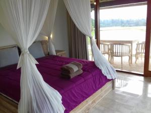 贾蒂卢维KUBU D'UME HOMESTAY的一间卧室配有一张带紫色床单的床和窗户。