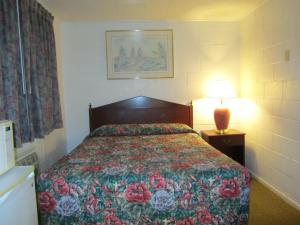 科蒂奇格罗夫格罗夫小屋休闲客栈的一间卧室配有一张带花卉床罩和灯的床。