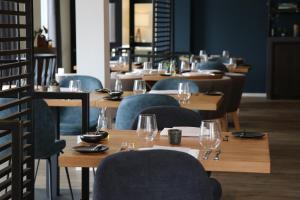 德科克斯多普特克赛尔精品酒店的餐厅设有木桌和椅子,配酒杯