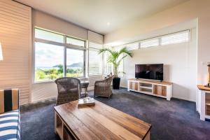 欧尼罗亚Waiheke Waterfront Lodge的客厅配有桌子和电视