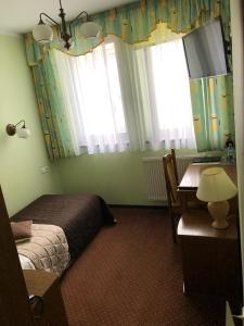 什切青普德赛酒店的卧室配有一张床、一张书桌和窗户。