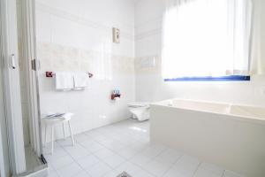 加尔达湖滨麦拉戈酒店的白色的浴室设有浴缸、卫生间和水槽。