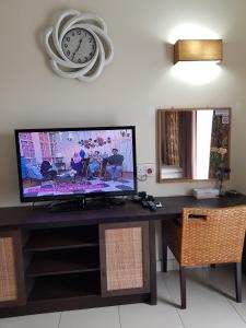 Kampong Tanjong PechahGold Coast Morib Ain Studio的桌子上的电视,墙上挂着时钟