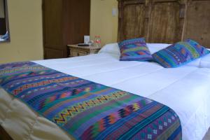 瓦哈卡市Hotel Boutique Casa Abuela Maria的一张白色的床,上面有色彩缤纷的毯子和枕头