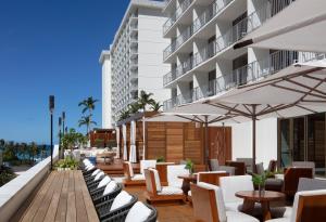 檀香山威基基海滩阿洛希拉尼酒店的酒店庭院配有桌椅和遮阳伞。