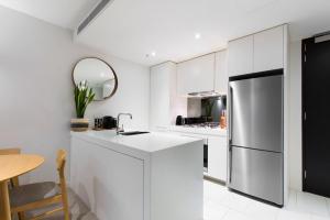 墨尔本Boutique Abode 313的厨房配有白色橱柜和不锈钢冰箱