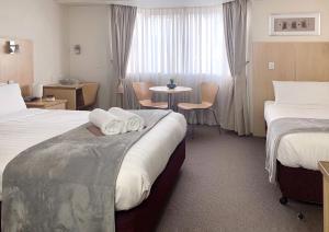 布里斯班阿斯科特机场汽车旅馆的酒店客房设有两张床和一张桌子。