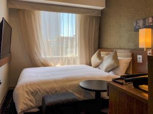 名古屋HOTEL UNIZO Nagoya Ekimae的酒店客房设有床和窗户。