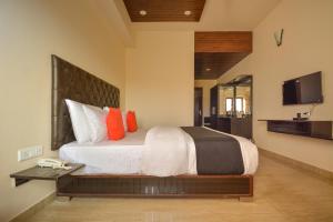 KuniharNakshatra Resort的一间卧室配有一张带橙色枕头的大床