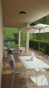 蒙福特达尔巴LE SETTE VIE HOLIDAY HOMES的庭院配有桌子、遮阳伞和椅子
