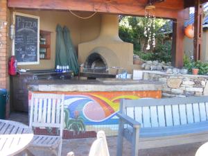 维德尼斯Wilderness Beach House Backpackers Lodge的一个带两个长椅和比萨饼烤箱的庭院