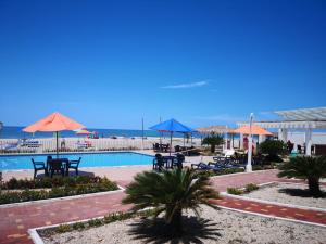普拉亚斯Villa Altamar的一个带桌子和遮阳伞的游泳池以及大海