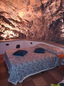 圭马尔Casa cueva El perucho的卧室在岩石墙前配有一张床